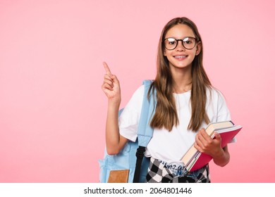 Excellent best student schoolgirl pointing with her fingers showing copy space wearing school bag isolated in pink background