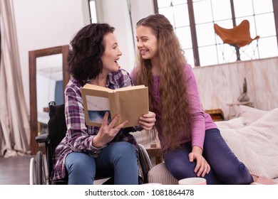 Excellent book. Joyful disabled woman holding book while girl grinning