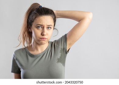 Excessive sweating problems. Young woman with her arm raised with her armpits sweat. - Shutterstock ID 2043320750