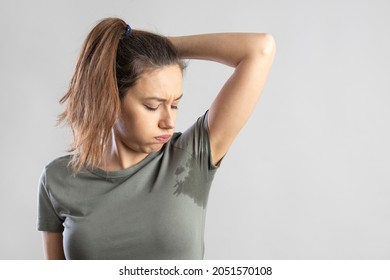 Excessive sweating problems. Young woman with her arm raised with her armpits sweat. - Shutterstock ID 2051570108