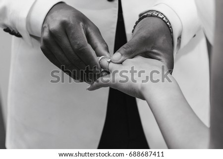exchanging wedding rings in black and white, black and white couple