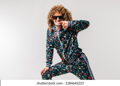 Excited Adult Funny Man In Stylish Vintage Clothes Posing On White Studio Background. 80s Fashion. Funky Guy In Tracksuit And Sunglasses Expressive Indoor Unusual Portrait. Shouting Cheerful Male.