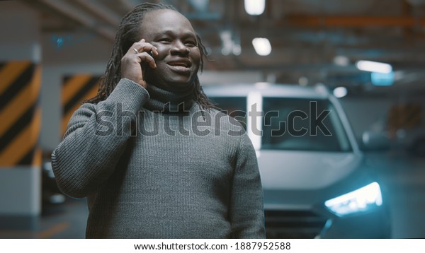 Excited african\
american black man having phone conversation in the underground\
parking. High quality\
photo
