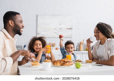 excited african american boy holding apple during breakfast with family - Powered by Shutterstock