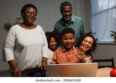 Excited African American Boy Waving Hand During Video Call Near Family