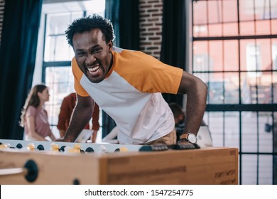 excited african american businessman looking at camera while playing table football in office - Powered by Shutterstock