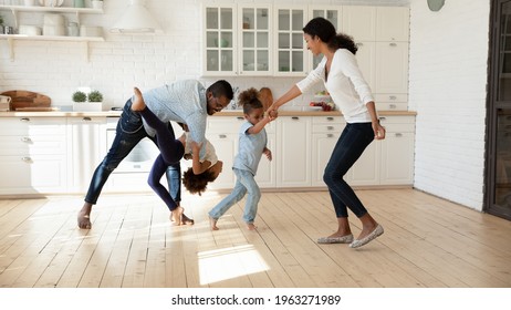 Excited African American family celebrating moving into new house. Happy parents and kids dancing in big modern kitchen interior, playing active games, exercising, having fun together at home party - Powered by Shutterstock