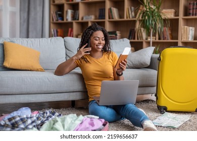 Excited African American Lady Using Laptop And Talking On Phone While Searching Summer Trip, Preparing For Holidays. Happy Woman Surfing Internet For Weekend Travel At Home