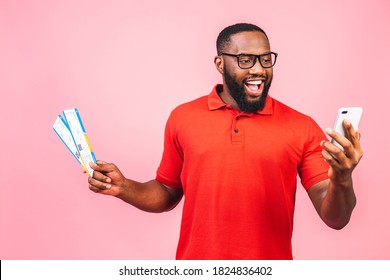 Excited African American Man In Casual Shirt Isolated On Pink Background. People Lifestyle Concept. Mock Up Copy Space. Holding Ticket, Holding Mobile Phone.