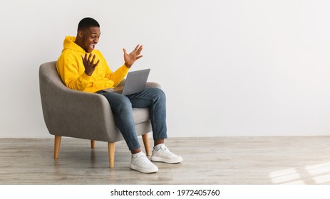 Excited African American Man With Laptop Shouting Celebrating Great Online News Sitting In Chair Over Gray Wall Indoor, Side View. Successful Freelance Career Concept. Panorama, Copy Space - Shutterstock ID 1972405760