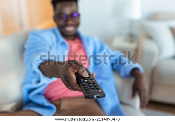 Excited African American\
Man Pointing Television Controller To Camera Switching Channels\
Watching TV . Television Programming Advertisement. Selective\
Focus