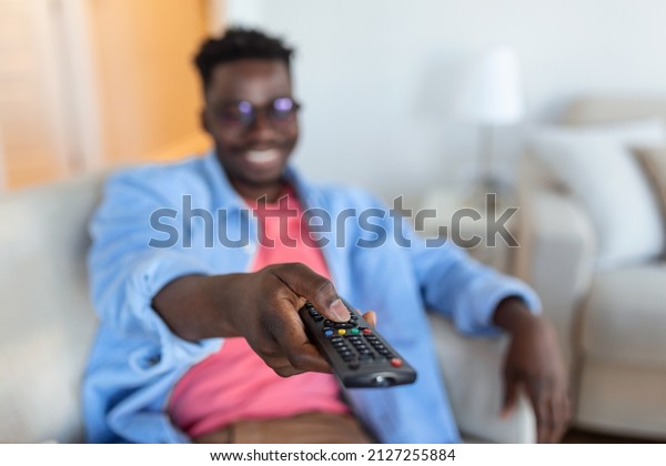Excited African American\
Man Pointing Television Controller To Camera Switching Channels\
Watching TV . Television Programming Advertisement. Selective\
Focus