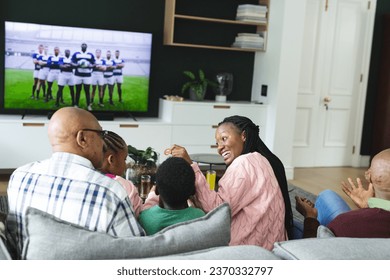 Excited african american parents, son, daughter and grandparents watching rugby on tv, slow motion. Sport, entertainment, home, family, togetherness, domestic life and lifestyle, unaltered. - Powered by Shutterstock