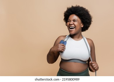 excited african american plus size woman in sportswear holding skipping rope isolated on beige - Powered by Shutterstock