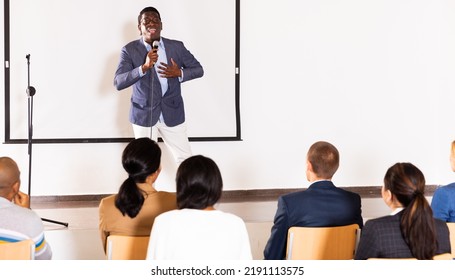 Excited African American Preacher Giving Motivational Speech To Business People From Stage In Conference Hall