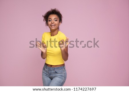Excited african american woman smiling, looking at camera, posing on pink pastel background.