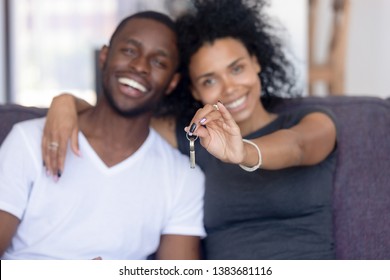 Excited African American Young Family Show Keys To Own Home, Happy Black Couple Sit On Couch Praise Buying First House Together, Smiling Husband And Wife Purchase New Property. Ownership Concept