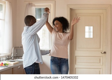 Excited african american young man dancing with happy mixed race wife, twisting, having fun together. Joyful smiling family couple moving, celebrating anniversary, enjoying weekend leisure time. - Powered by Shutterstock