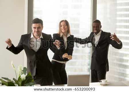 Excited african and caucasian employees dancing in office, staff party, positive multi-ethnic team satisfied with result, won profitable contract, group of winners celebrate victory or great success 