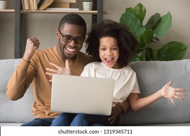 Excited african father and kid girl feel winners looking at computer screen, happy black dad with child daughter using laptop rejoice online game win, great internet news, celebrate victory together