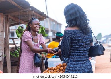 Excited African female fruit merchant happily satisfying a customer, exchanging goods at a vibrant fruit market stall - Powered by Shutterstock