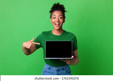 Excited african girl presenting laptop with black blank screen for mock up, isolated on green studio wall, empty space - Powered by Shutterstock