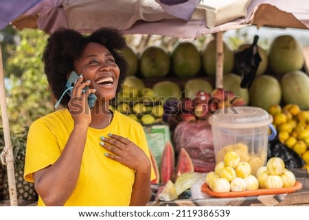 excited african lady making a phone call in a market