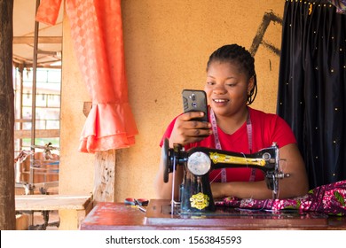 Excited African Local Small Business Tailor Using Her Mobile Phone Checking Notification For Good News