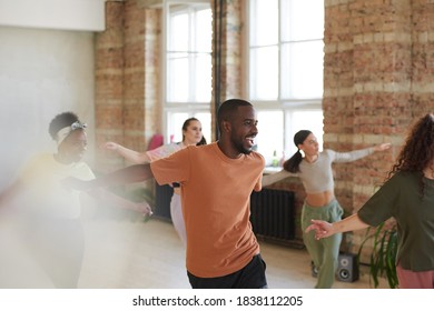 Excited African man dancing together with other young people in dance studio