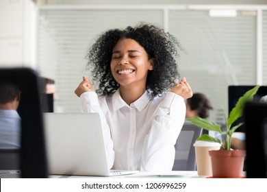 Excited african office worker student receiving good news in email on laptop, motivated happy black female employee getting promoted or rewarded celebrating great result achievement win opportunity