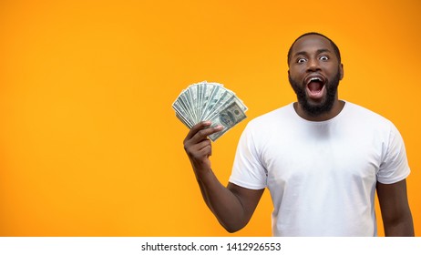 Excited Afro-American man holding bunch of dollar, crowd funding or start-up - Shutterstock ID 1412926553