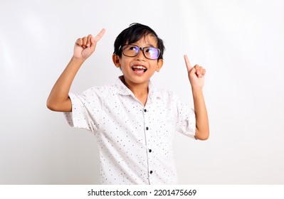 Excited Asian Boy Standing While Pointing And Looking Up. Isolated On White Background