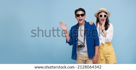 Excited Asian couple tourist dressed in summer clothes to travel on holidays isolated on blue copy space background.
