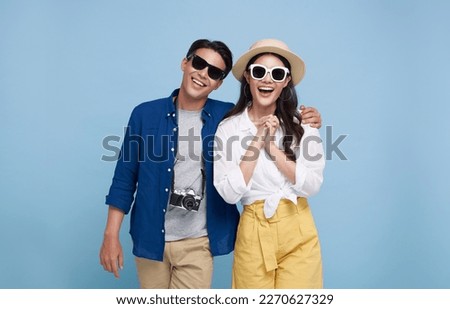 Excited Asian couple tourist dressed in summer clothes to travel on holidays isolated on blue background.