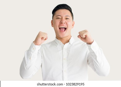 Excited Asian Guy Raising Fists In Success