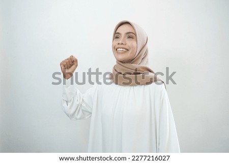 Excited Asian Muslim woman celebrating victory isolated over whi