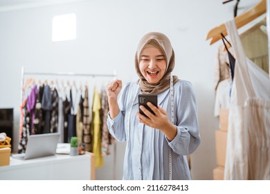 excited asian muslim woman small business owner look at phone