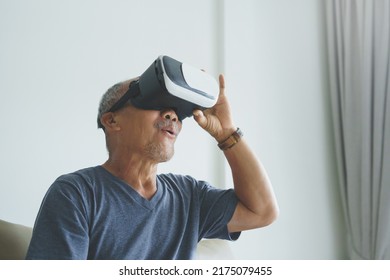 Excited Asian Senior man wearing VR goggles and enjoying playing video games with virtual reality headset - Powered by Shutterstock