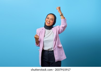 Excited Asian woman celebrating success with laugh expression over blue background