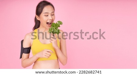 Excited asian woman holding fresh green kale leaf on pink background with copy space. Smile young girl eat freshness kale leaf superfood for diet healthy over isolated. Plants vegan superfood concept.