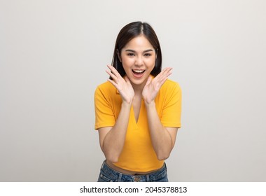 Excited asian woman shout out loud wow with hands on isolated background. Happy shocked face female wow promotion advertising concept. Joyful teenage girl in yellow shirt standing in white room.