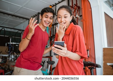 Excited Asian Young Couples At Bike Shop Suprised While Looking At Phone