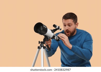Excited astronomer with telescope on beige background. Space for text