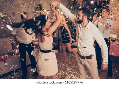 Excited attractive charming beautiful cheerful well-dressed couple, husband spinning elegant alluring wife, ladies and handsome gentlemen at home festive, chill out, glitter falling down around