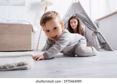 excited baby boy crawling on floor near mother on blurred background - Powered by Shutterstock