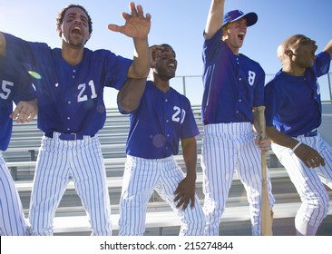 Excited Baseball Team Jumping Up From Bench In Stand During Competitive Baseball Game, Cheering, Front View (backlit)