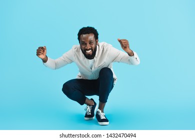 Excited Bearded African American Man Sitting Isolated On Blue