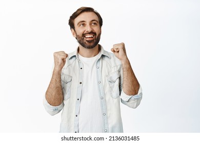 Excited bearded guy looking up and rejoicing from winning, triumphing and celebrating over great news, studio background. - Shutterstock ID 2136031485