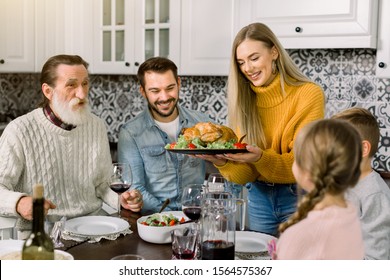 Excited Beautiful Family Looking At Thanksgiving Turkey. Young Woman Holds The Plate With Roast Chicken Or Turkey