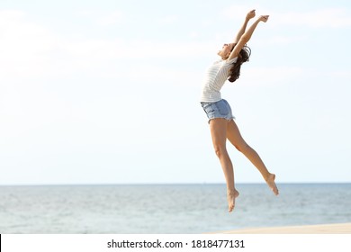 Excited beautiful woman with long legs jumping on the beach celebrating summer vacation